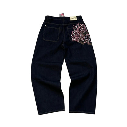 Black jeans with floral embellishments on a textured gray surface