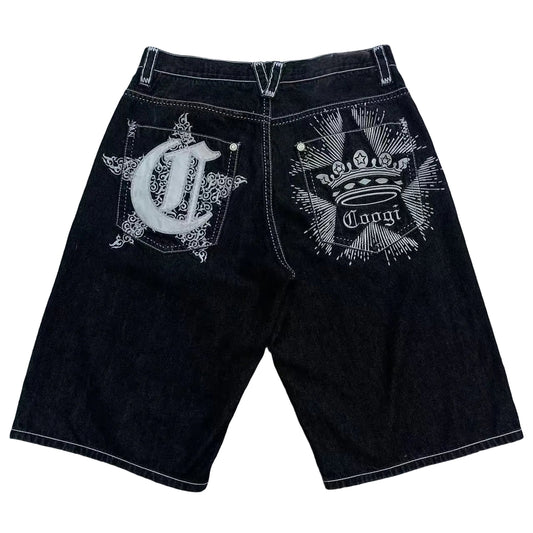 Black shorts with white embroidery on a gray surface