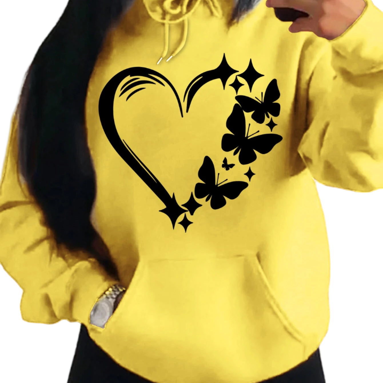 Yellow hoodie with black heart and butterfly design worn by a person.