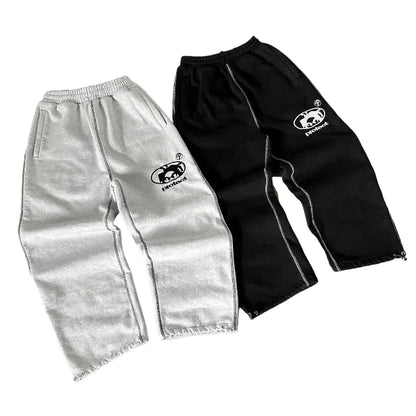 Two pairs of pants, one gray and one black, with a logo on a gray surface.