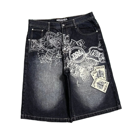 Black denim shorts with white embroidery on a green and white checkered background