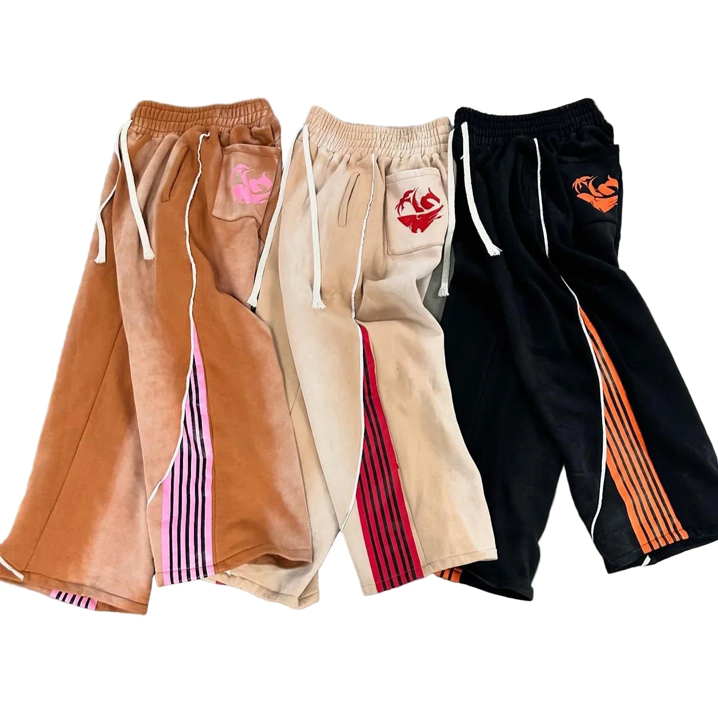 Three pairs of colorful pants with designs on a gray surface