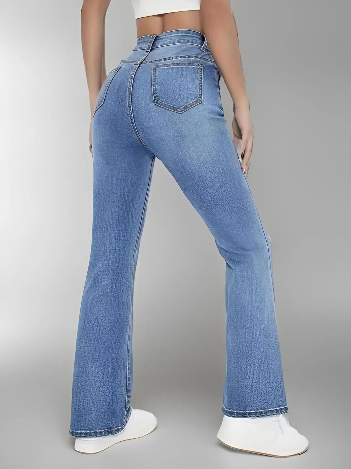 Person wearing blue flared jeans on a gray background