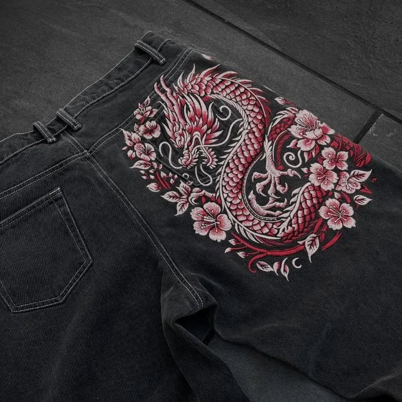 Black denim jacket with red and pink dragon embroidery on a dark surface