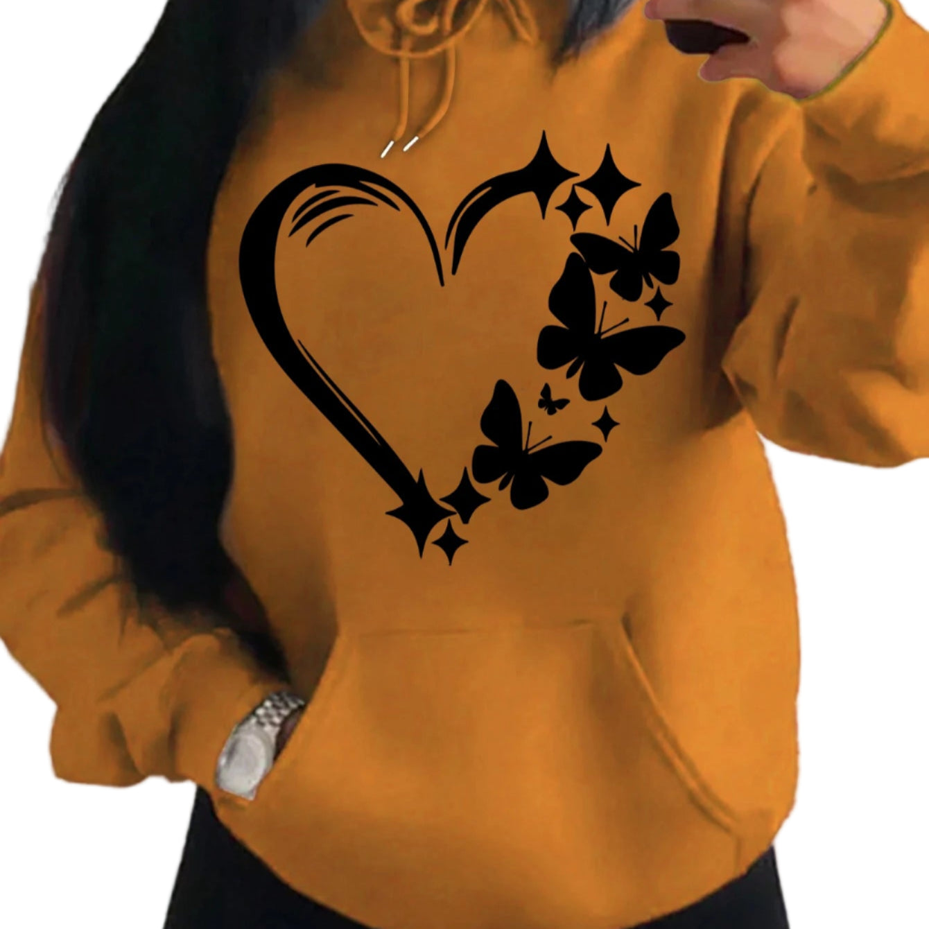 Person wearing a mustard yellow hoodie with black heart and butterfly design.