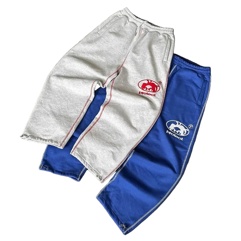 Two pairs of pants, one gray and one blue, with logos on a gray surface.