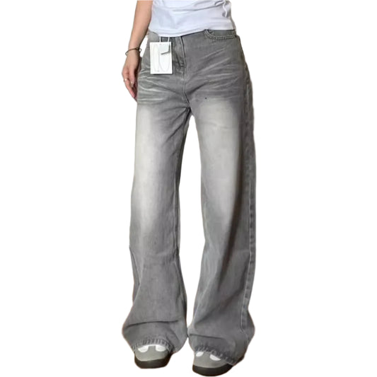 Person wearing gray flared jeans indoors on a wooden floor.