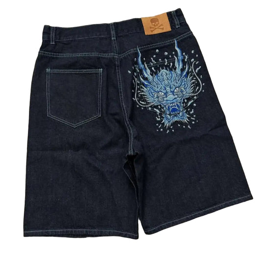 Black denim shorts with blue graphic design on a concrete floor