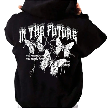 Person wearing a black hoodie with butterfly design and text on the back, standing against a metallic shutter.