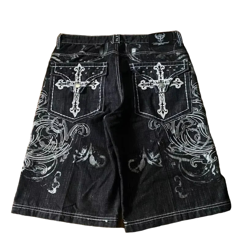 Black denim shorts with white embroidery on a wooden surface