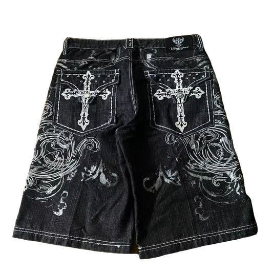 Black denim shorts with white embroidery on a wooden surface