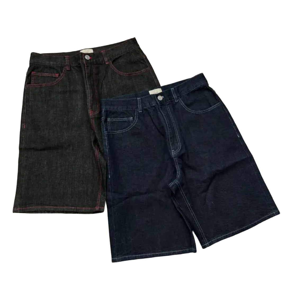 Two pairs of denim shorts, one black and one dark blue, on a gray concrete surface.