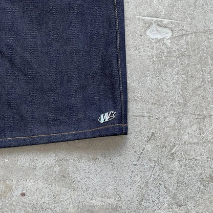 Close-up of a blue denim fabric corner with a logo on a concrete surface