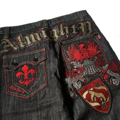 Dark denim jeans with red and gold embroidery on a white fabric background