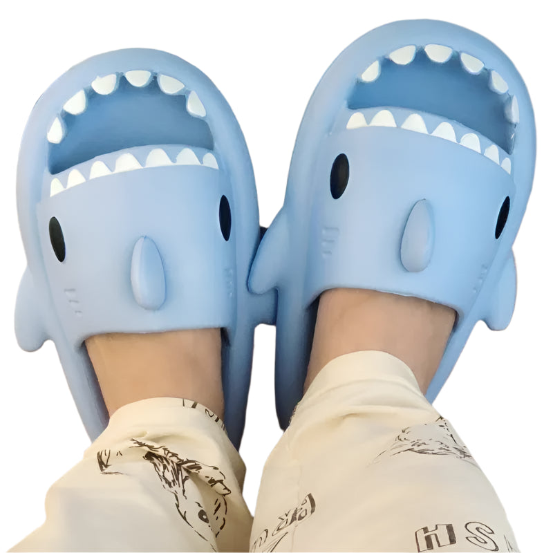 Blue shark-shaped slippers worn indoors on a wooden floor.