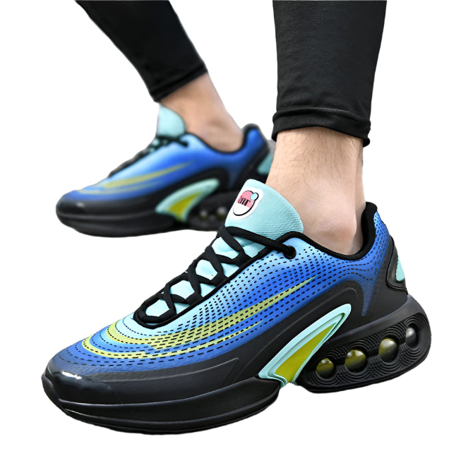 Blue and black athletic shoes with yellow accents worn on a road.