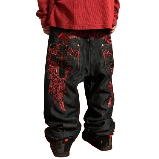 Person wearing black pants with red embroidery in a room with a red carpet.