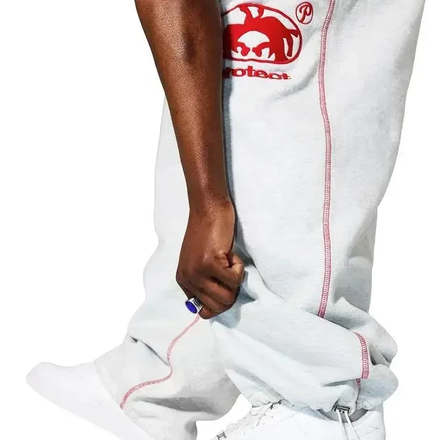 White pants with red stitching and a logo, worn by a person, on a white background.