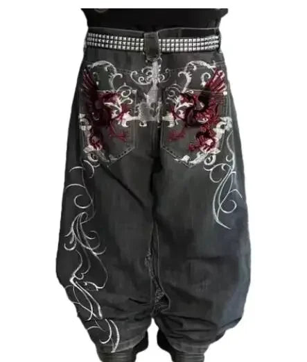 Black pants with floral embroidery and studded waistband on a white background