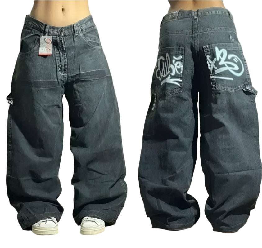 Pair of baggy jeans with visible branding on a wooden floor.