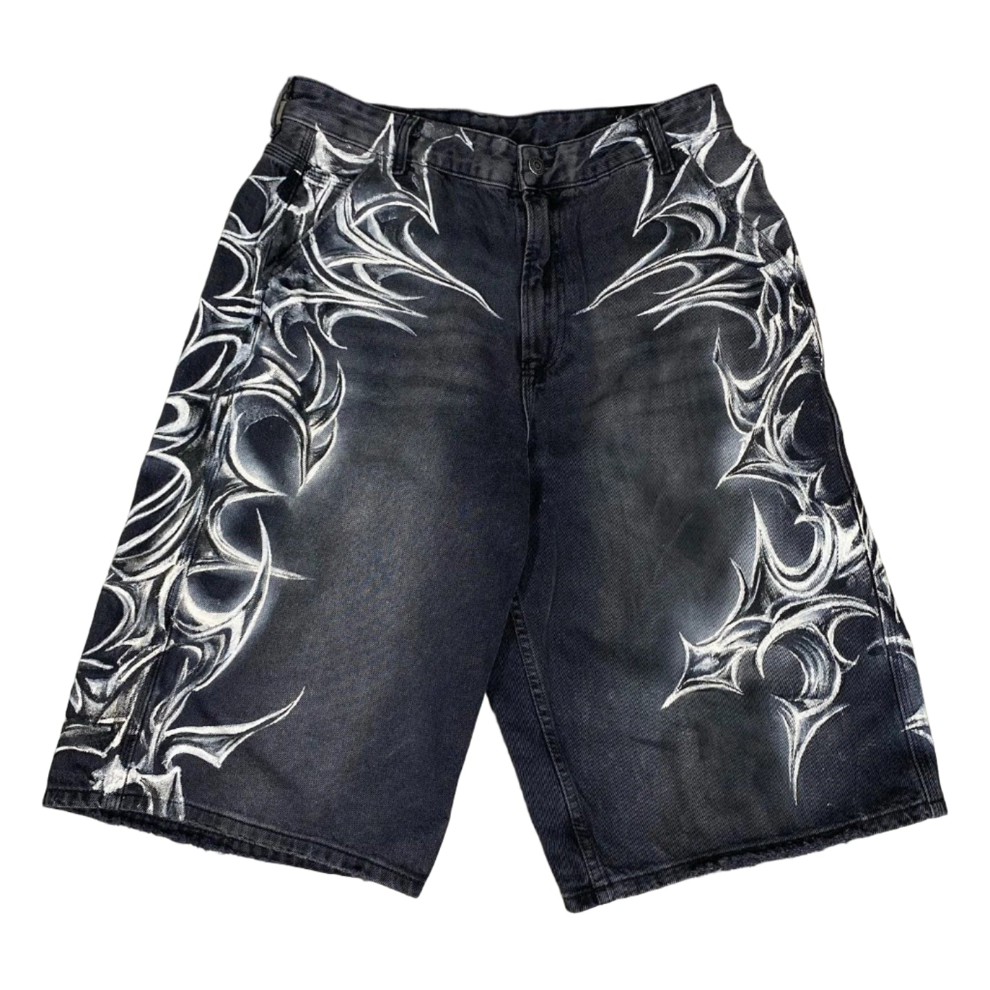 Black denim shorts with white tribal patterns on a concrete floor