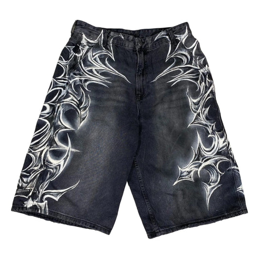 Black denim shorts with white tribal patterns on a concrete floor