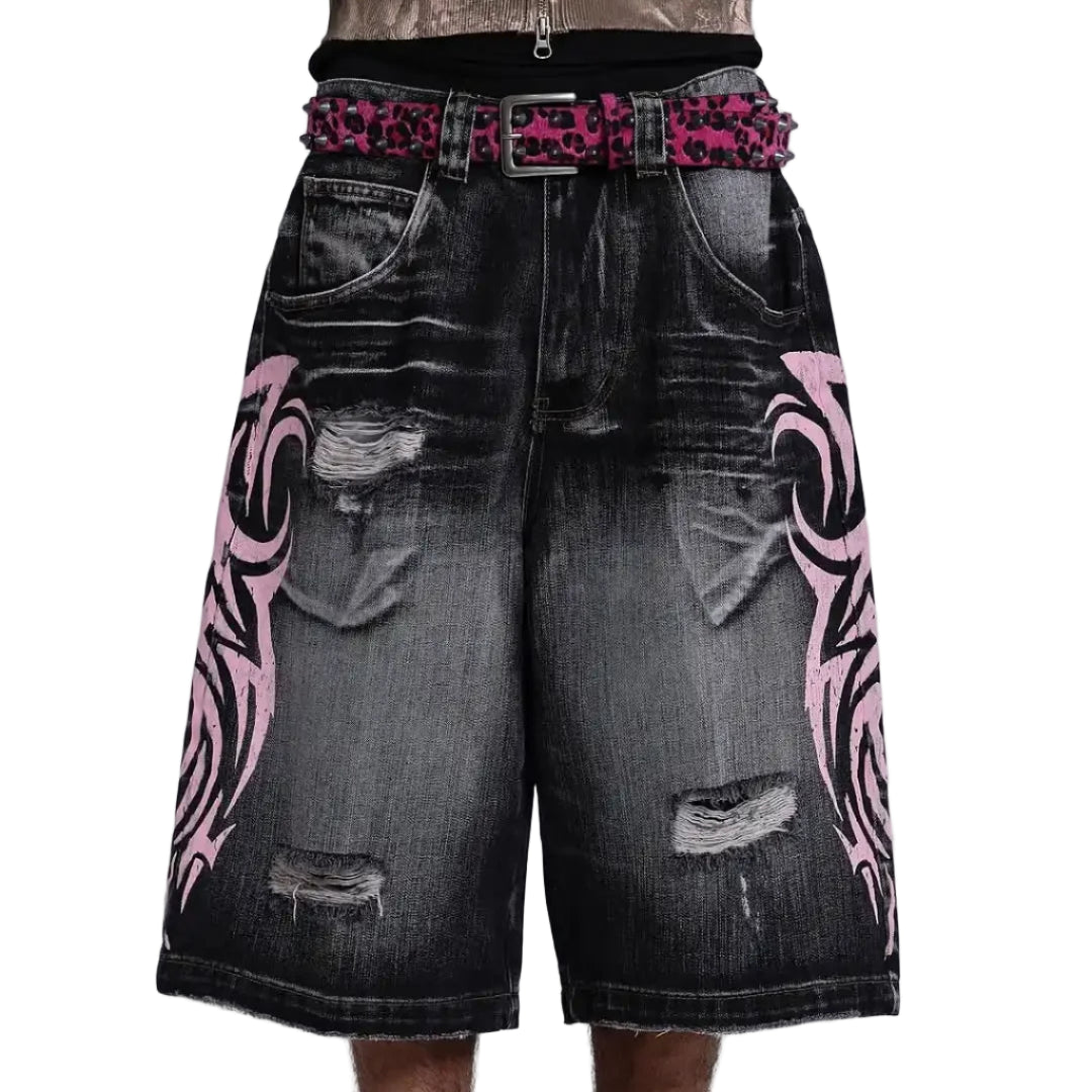 Black denim shorts with pink tribal patterns and a studded belt on a light gray background