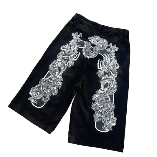 Black shorts with white dragon design on a concrete surface