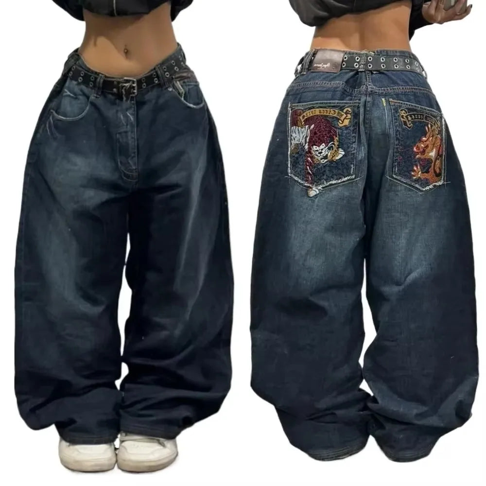 Pair of blue jeans with embroidered designs on the back pocket, worn by a person.
