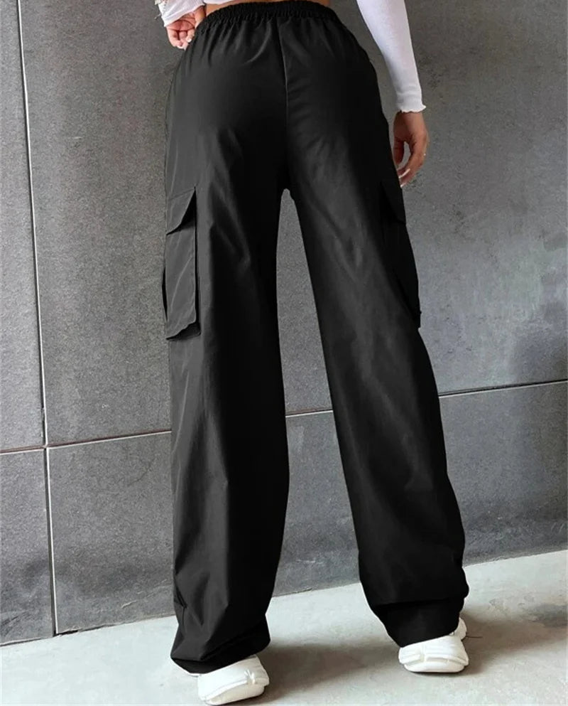 Person wearing black cargo pants with a gray wall background