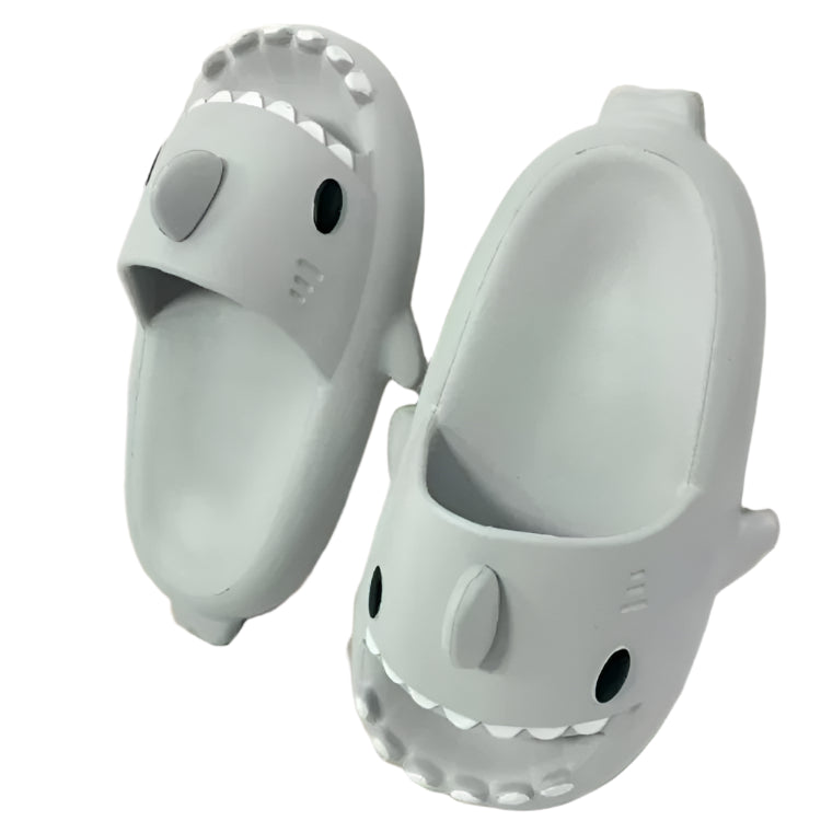 Pair of shark-shaped slippers on a wooden floor.