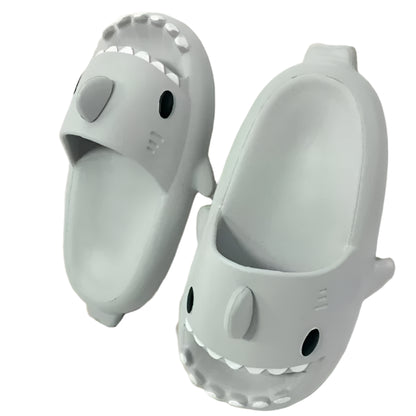 Pair of shark-shaped slippers on a wooden floor.