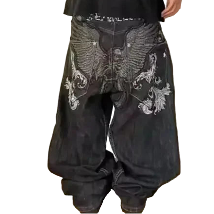 Person wearing black baggy pants with white embroidery on a plain background